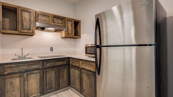 A kitchen with wooden cabinets, a stainless steel refrigerator, and a built-in oven.