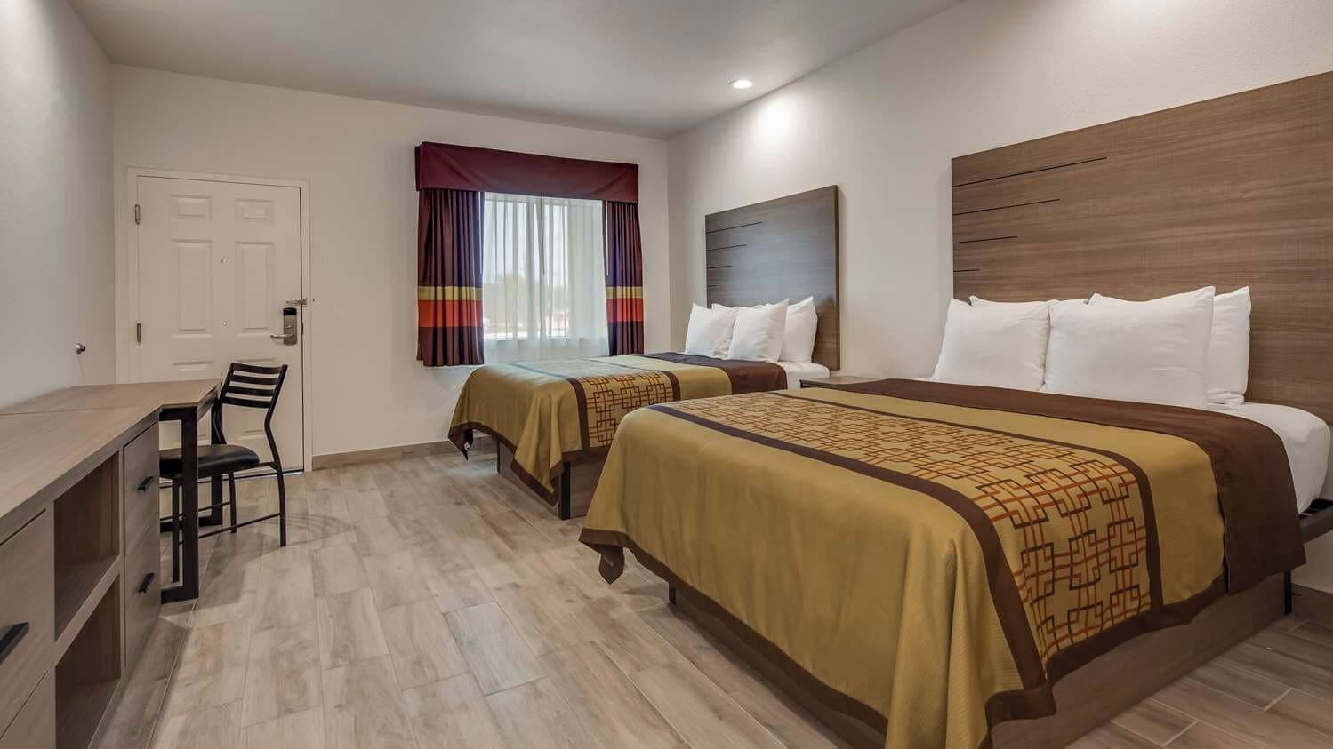 Een hotelkamer met twee bedden, een bureau en een stoel.