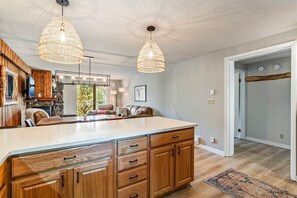 Een ruime keuken met een groot eiland, houten keukenkastjes en hanglampen.