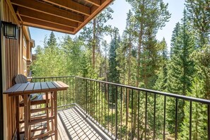 Una terrassa de fusta amb barana metàl·lica que faig vista a un bosc.
