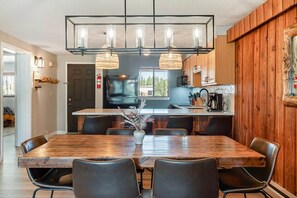 A modern kitchen with a wooden island, black chairs, and pendant lights. - Howling Wolf Winter Park Ski/Hike/Bike Condo (Winter Park)