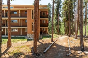 A multi-story building with balconies, surrounded by a forested area. - Howling Wolf Winter Park Ski/Hike/Bike Condo (Winter Park)