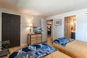 Een slaapkamer met twee bedden, een bureau, een stoel en een televisie.