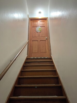 A wooden staircase leading to a door with a sign above it. - Cozy 2 bedroom Upper Duplex w/ Bonus Room (New Berlin)