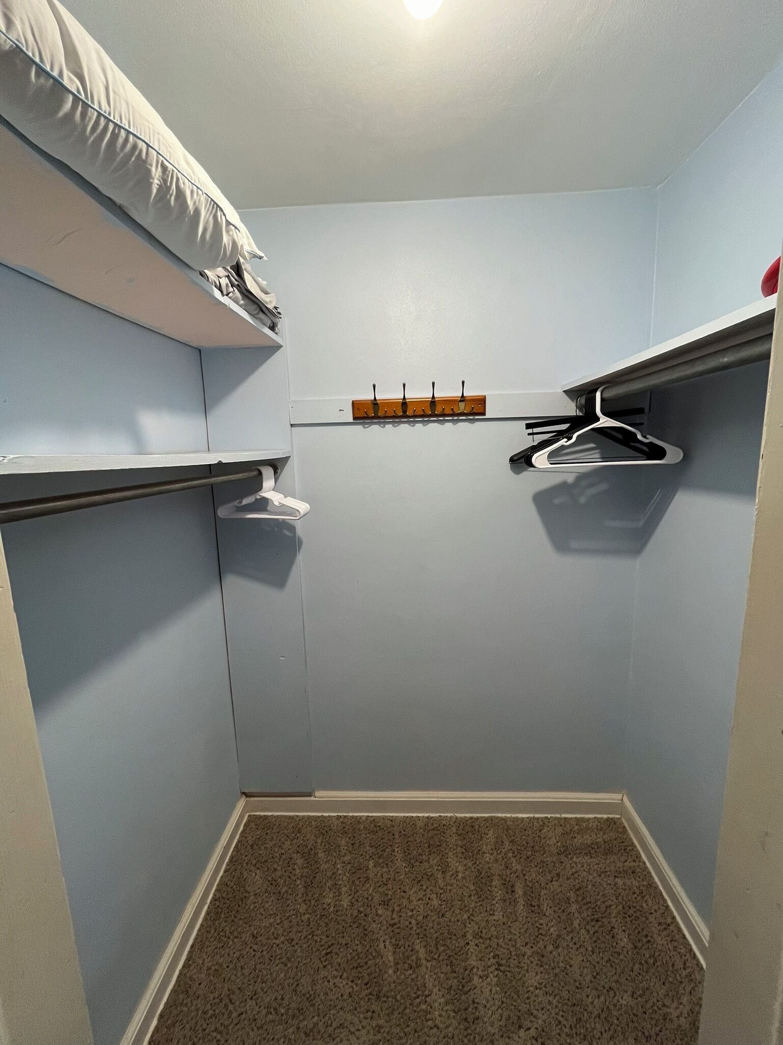 Ein kleiner, abgeschlossener Raum mit Schrank, Kleiderhaken und Ablagefläche.