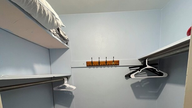 Ein kleiner, abgeschlossener Raum mit Schrank, Kleiderhaken und Ablagefläche.
