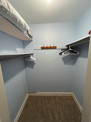 A small, enclosed room with a closet, a coat rack, and a shelf.