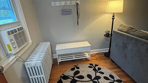 Ein Zimmer mit Heizkörper, einer weißen Bank, einer Lampe und einem gemusterten Teppich.
