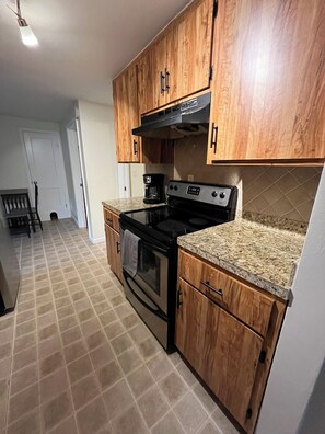 A kitchen with wooden cabinets, a stove, and a coffee maker.
