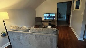 Ein Wohnzimmer mit einer Couch, einem Fernseher und einer Lampe.