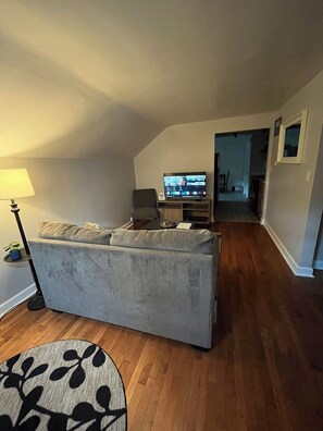 A living room with a sofa, a TV, and a lamp. - Cozy 2 bedroom Upper Duplex w/ Bonus Room (New Berlin)