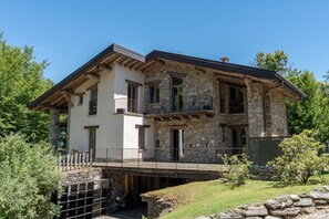 A two-story stone building with a balcony, a wooden bridge, and a stone wall.