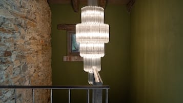 Een kroonluchter hangt aan het plafond in een kamer met stenen muren en een houten balk.