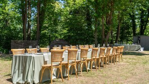 An outdoor dining setup with tables and wicker chairs arranged in rows.