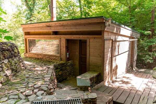 A wooden cabin with a stone foundation, a door, and a window.