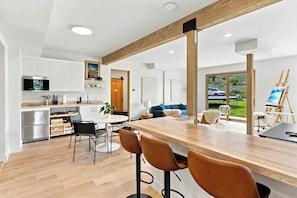 Una cocina moderna con armarios blancos, encimera de madera y un comedor con una mesa grande y taburetes de bar.