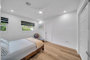 A bedroom with a bed, a chair, a window, and a door. - Unique 4-bedroom house with pool and gulf access in lovely Fort Myers (Fort Myers)