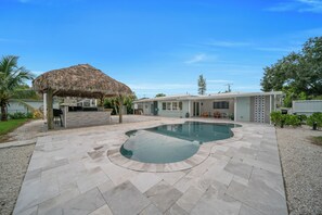 A modern house with a swimming pool, a thatched-roof structure, and a well-maintained garden. - Unique 4-bedroom house with pool and gulf access in lovely Fort Myers (Fort Myers)