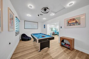A modern room with a pool table, a projector screen, and a ceiling-mounted projector. - Unique 4-bedroom house with pool and gulf access in lovely Fort Myers (Fort Myers)