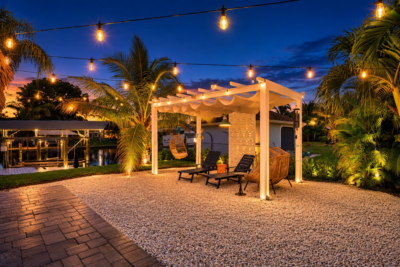 Un espace extérieur aménagé avec une pergola, des guirlandes lumineuses et des sièges, avec une piscine en arrière-plan.