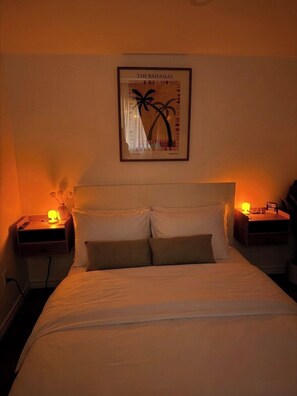 A hotel room with a bed, two nightstands, a framed picture of palm trees, and two bedside lamps. - Cozy Detached Garden Guesthouse | Private Studio (Hamilton)