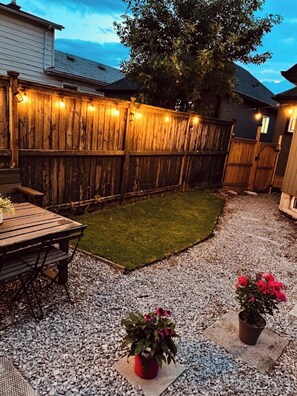 A backyard with a wooden fence, a grassy area, a gravel path, and two potted plants. - Cozy Detached Garden Guesthouse | Private Studio (Hamilton)