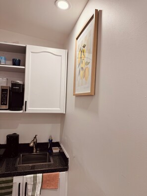 A kitchen with a coffee maker, a sink, and a framed picture on the wall. - Cozy Detached Garden Guesthouse | Private Studio (Hamilton)