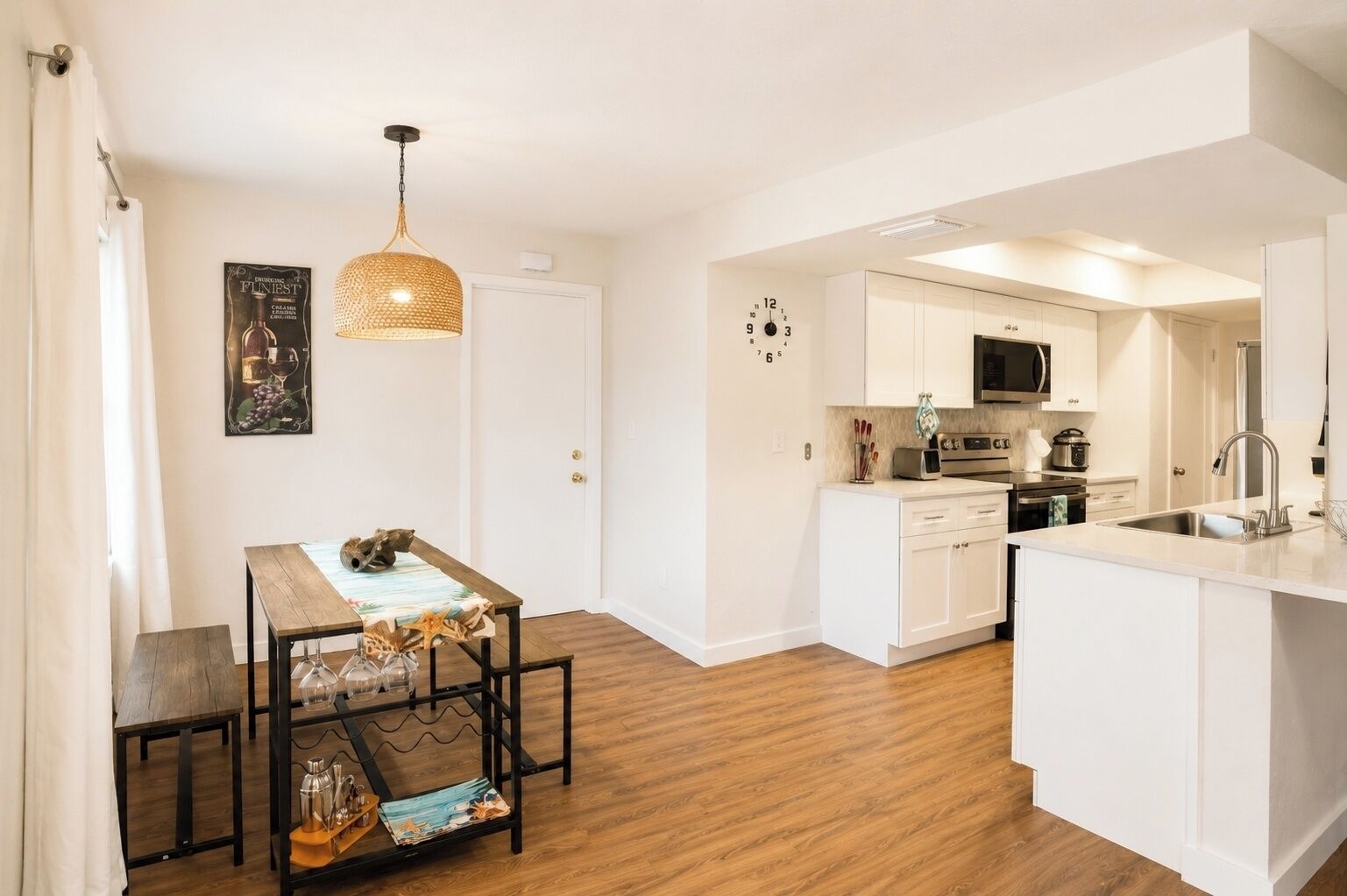 A modern kitchen with white cabinetry, a built-in microwave, and a stainless steel sink.