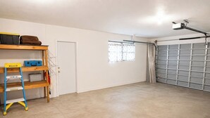 Een garage met een gesloten garagedeur, een werkbank met gereedschap en een ladder.
