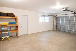 Un garage avec une porte fermée, un établi avec des outils et une échelle.