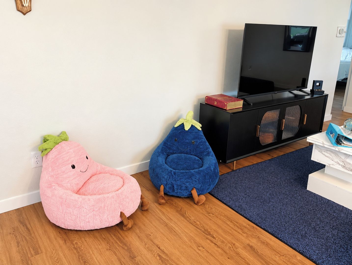 A room with a television, a cabinet, and two bean bag chairs.