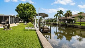 Een pand aan het water met een overdekte steiger, een gazon en een huis met een veranda.