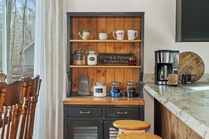 A kitchen counter with a coffee station, including jars labeled sugar, tea, and coffee, and a sign that reads 'Coffee & Friends.' - Campfire Nights Start Here. Fireplace, Game Loft & Fall Adventures (Blakeslee)