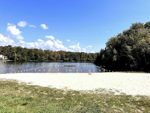 A lake with a sandy beach, a row of buoys, and a forested area in the background. - Campfire Nights Start Here. Fireplace, Game Loft & Fall Adventures (Blakeslee)