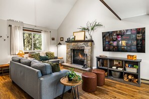 A cozy living room with a fireplace, a sofa, a coffee table, and a bookshelf. - Where Fall Memories Are Made! Hiking, Campfire Nights, Games, Cozy Fireplace (Blakeslee)