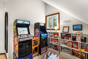 A room with two arcade machines, a window with a view, and shelves with board games. - Where Fall Memories Are Made! Hiking, Campfire Nights, Games, Cozy Fireplace (Blakeslee)