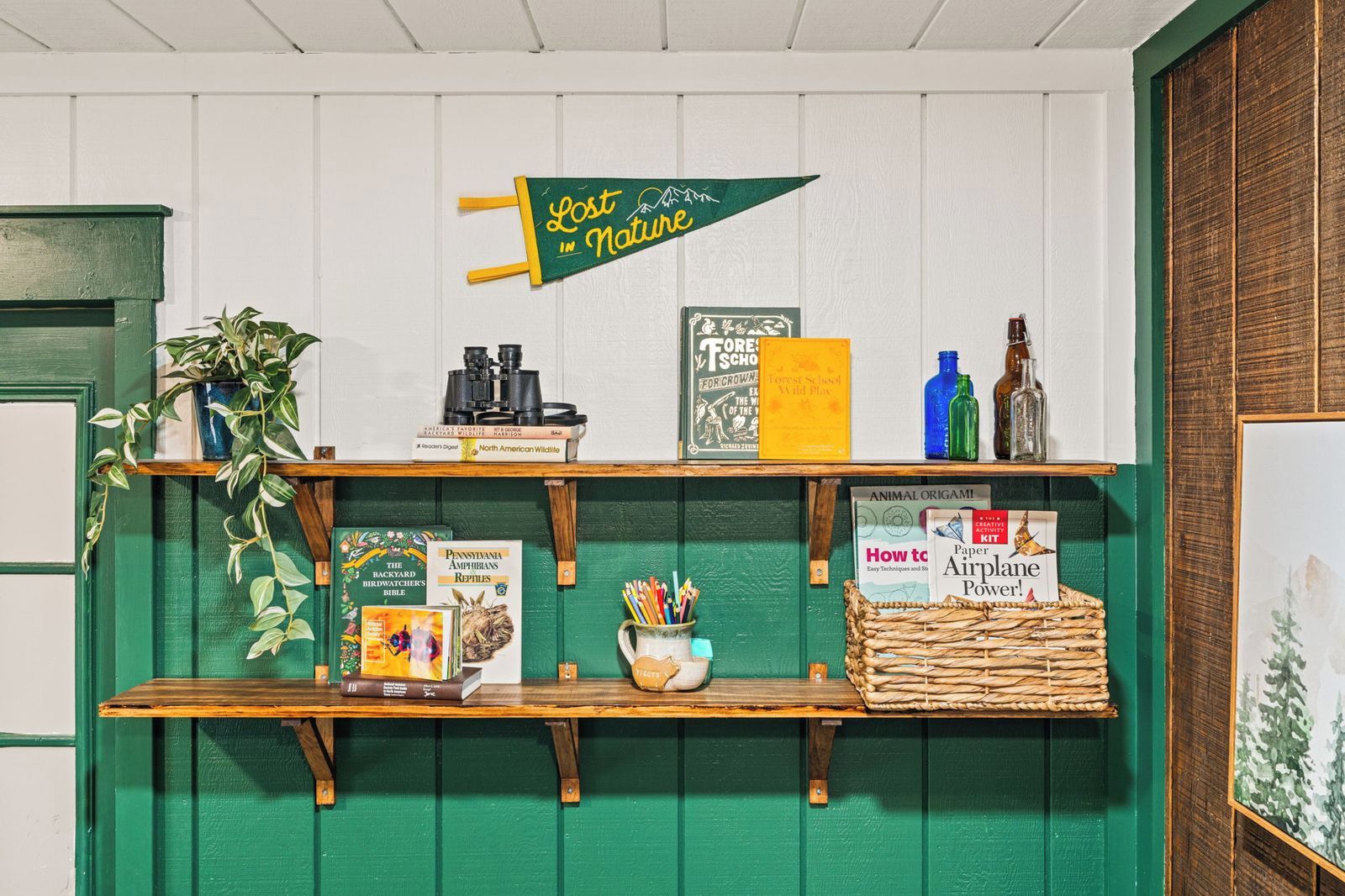 A shelf with books, binoculars, a plant, and a sign that says 'Lost in Nature'.