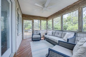 A covered porch with wicker furniture, a ceiling fan, and large windows. - 1615 - Smallfield Shores - Oceanside Corolla retreat with 4 bedrooms, ocean view, pool, hot tub. (Corolla)