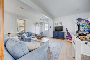 A living room with a sofa set, a coffee table, a television, and a foosball table. - 1615 - Smallfield Shores - Oceanside Corolla retreat with 4 bedrooms, ocean view, pool, hot tub. (Corolla)