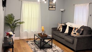 A living room with a grey sofa, a coffee table, a black floor lamp, and a ceiling light fixture. - Stylish 2-bedroom apartment with AC in near FLL airport & Hollywood beach (Hollywood)