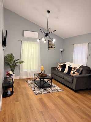 A living room with a grey sofa, a coffee table, a black floor lamp, and a ceiling light fixture. - Stylish 2-bedroom apartment with AC in near FLL airport & Hollywood beach (Hollywood)