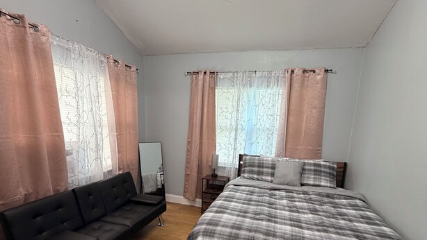 A bedroom with a bed, a sofa, a nightstand, and curtains. - Stylish 2-bedroom apartment with AC in near FLL airport & Hollywood beach (Hollywood)