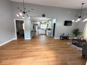 A spacious living room with a wooden floor, a dining area with a table and chairs, a kitchen with modern appliances, and a ceiling fan. - Stylish 2-bedroom apartment with AC in near FLL airport & Hollywood beach (Hollywood)