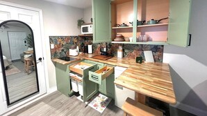 Una cocina compacta con armarios verdes, un microondas y una encimera de madera.