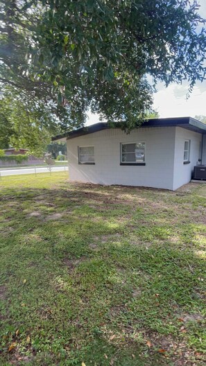 A small, single-story building with a flat roof, surrounded by grass and a tree.