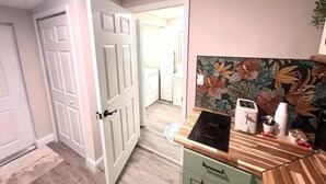 Una cocina con mostrador, cafetera y puerta que da a otra habitación.