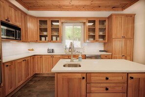 Une cuisine avec des meubles en bois, un évier en acier inoxydable, un four à micro-ondes et une fenêtre.