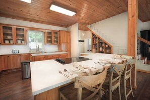 Eine moderne Küche mit Holzausstattung, einer großen Kochinsel und einem Essbereich mit Stühlen.