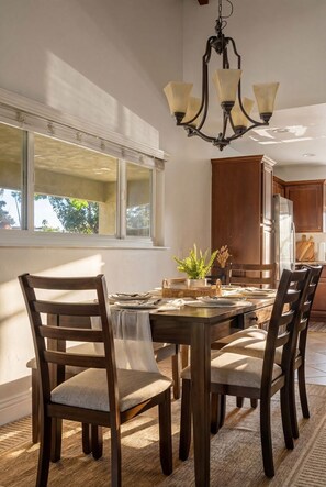 A dining area with a wooden table, chairs, and a chandelier. - San Diego Pool Home Oasis with Backyard Retreat (San Diego)