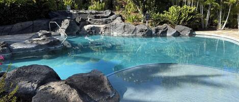 A clear pool with rock formations and tropical vegetation.